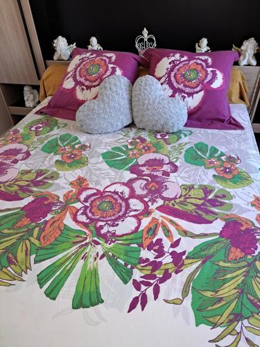 a bed with a floral bedspread and pillows on it at Studio de charme à Bouillante, 100 m², vue sur mer et montagnes in Bouillante
