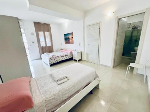 a white bedroom with two beds and a mirror at Blu Marzamemi Rooms in Marzamemi