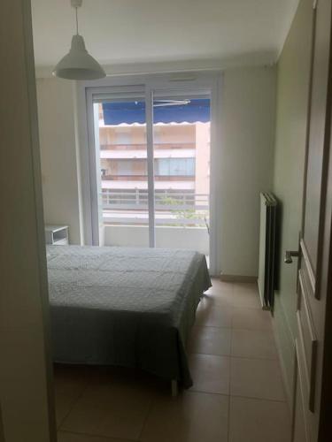 une chambre avec un lit et une grande fenêtre dans l'établissement Appartement 3 pièce à Cannes, à Cannes