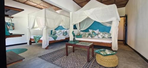 a bedroom with a canopy bed and a table at La VILLA BORAHA 300m2 PROPRIÉTÉ ENTIERE en bord de plage PISCINE PRIVEE Cuisine TV Wifi in Sainte Marie