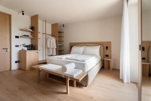 a bedroom with a large white bed and a bench at Hotel Al Maso in Riva del Garda