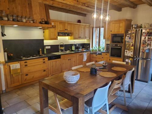 une grande cuisine avec une table et des chaises en bois dans l'établissement Grande maison savoyarde ensoleillée, à Villard-sur-Boëge