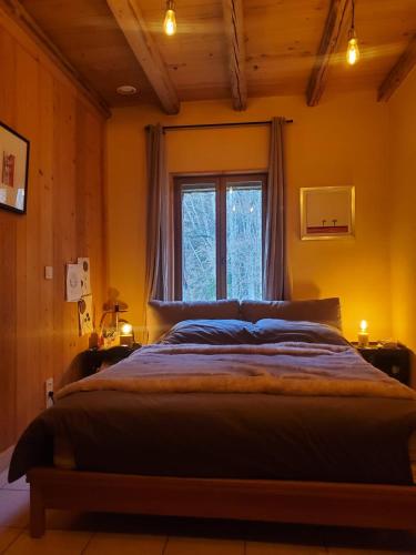 - une chambre avec un grand lit en face d'une fenêtre dans l'établissement Grande maison savoyarde ensoleillée, à Villard-sur-Boëge