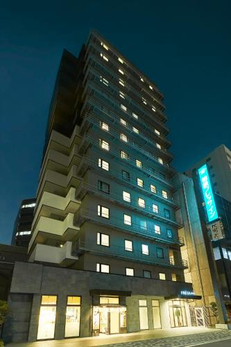 a tall building with a sign on it at night at Sotetsu Fresa Inn Kitahama in Osaka