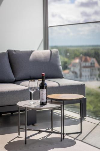 a bottle of wine sitting on a table next to a couch at Côte de la Mer, Ultra Luxurious, Sea View, use of shared pool and sauna in Cadzand