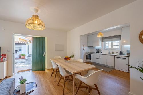 a kitchen and dining room with a wooden table and chairs at Casa da Vigia - Santa Cruz - Casa com Jardim a 4 Min da Praia in A dos Cunhados
