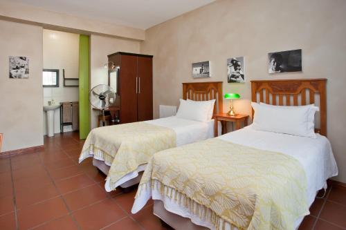 a hotel room with two beds and a bathroom at Miles B&B Guest House in Oudtshoorn
