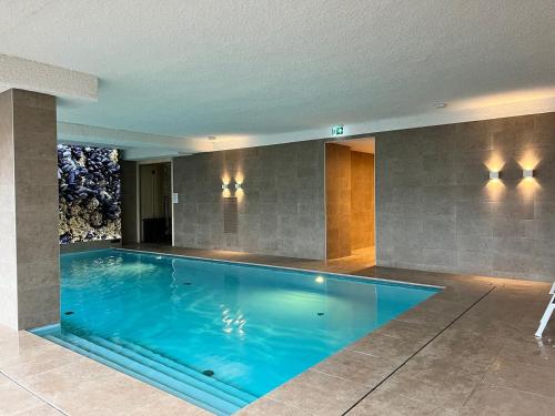 a large swimming pool in a room with at Côte de la Mer, Ultra Luxurious, Sea View, use of shared pool and sauna in Cadzand
