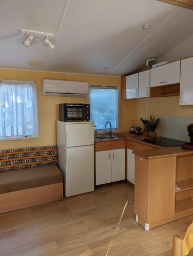 une cuisine avec des armoires blanches et un réfrigérateur blanc dans l'établissement Mobilhome tout confort dans domaine boisé, au Castellet