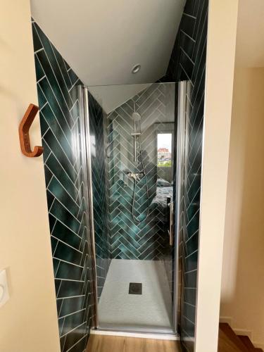 Una ducha a ras de suelo en un baño con azulejos verdes. en maison de la marine, en Dives-sur-Mer