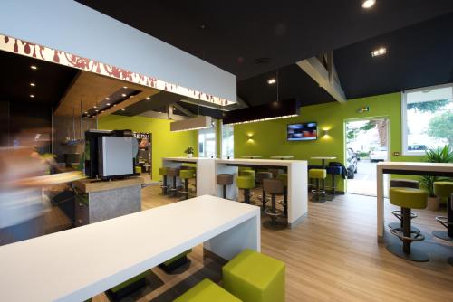 a restaurant with green walls and a white table and chairs at ibis budget Saint Paul Les Dax in Saint-Paul-lès-Dax