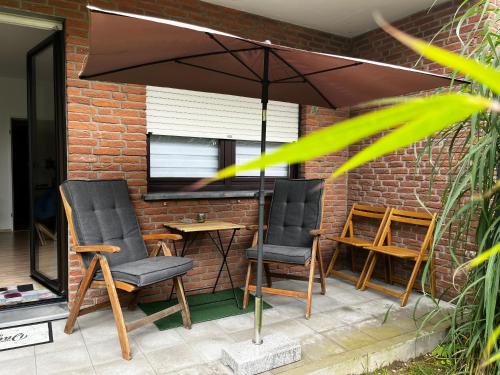 two chairs and an umbrella on a patio at KATARINAS HOUSE mit 2 FeWo stilvoll, gemütlich & zentral Boxspringbett, Parkplatz, Balkon oder Garten in Moers
