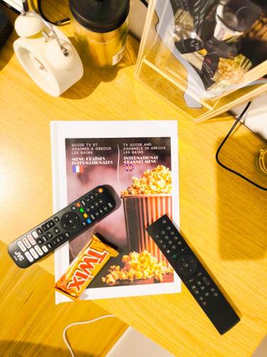 two remote controls and a box of popcorn and a movie at Le King & Suites étoilées in Gréoux-les-Bains