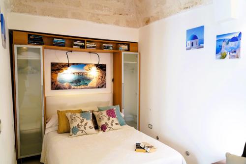 a small bedroom with a bed with white sheets and pillows at Dimora Le Vele - ELEGANZA con VISTA MARE in Ostuni