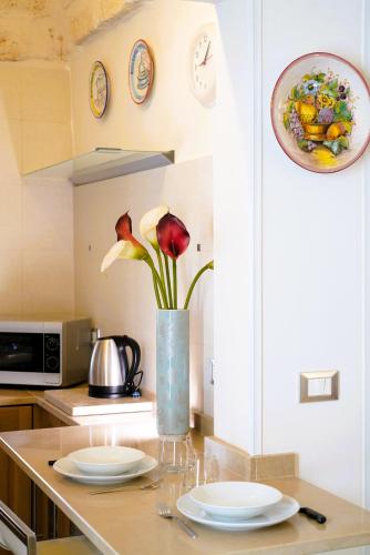 a kitchen counter with plates and a vase with flowers at Dimora Le Vele - ELEGANZA con VISTA MARE in Ostuni