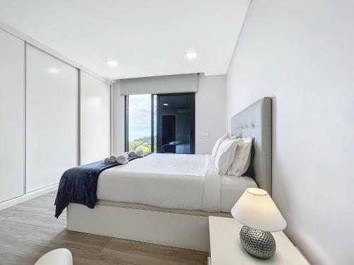 een witte slaapkamer met een bed en een raam bij Gertrudes Dream House in Ponta do Sol