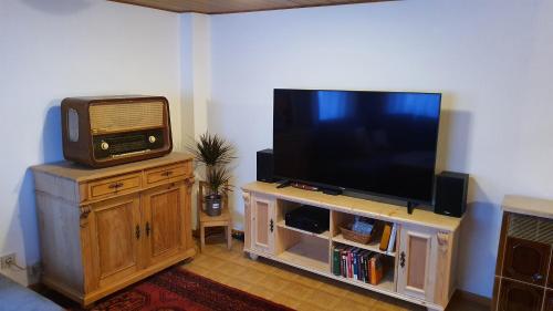 a living room with a tv on top of a wooden entertainment center at Gemütliches Haus im alten Ortskern in Wehrheim