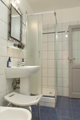 a white bathroom with a sink and a shower at Nonnakatia in Riomaggiore