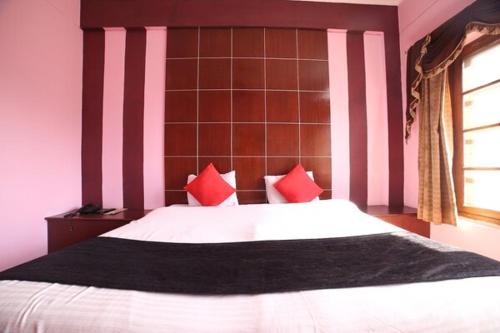 a bedroom with a large white bed with red pillows at Mansarover Hotel & Banquets in Bareilly