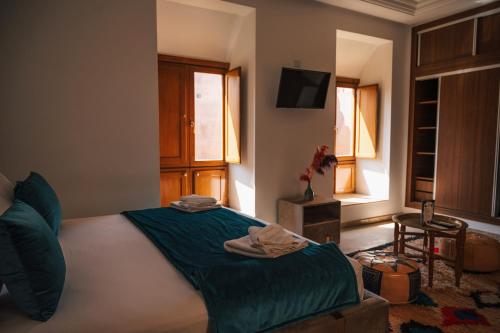 a bedroom with a bed and a tv and a window at Riad Kenza in Marrakech