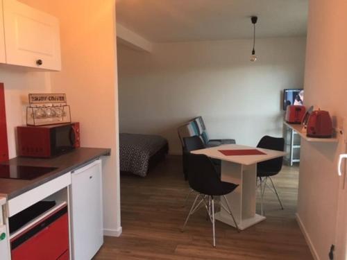 eine Küche mit Tisch und Stühlen in einem Zimmer in der Unterkunft Beau studio appart meublé à La Suze Dispo septembre 2025 in La Suze-sur-Sarthe