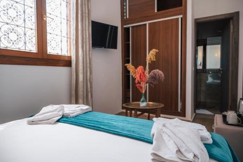 a bedroom with a bed with a vase of flowers on it at Riad Kenza in Marrakech