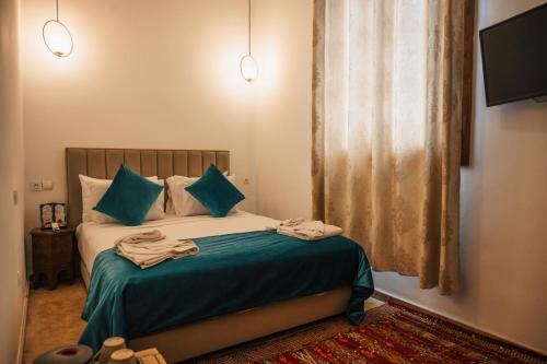 a bedroom with a bed with green sheets and blue pillows at Riad Kenza in Marrakech