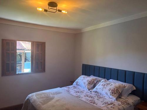 a bedroom with a bed with a blue headboard and a window at Maravilhoso sítio com piscina e churrasqueira in São José dos Campos