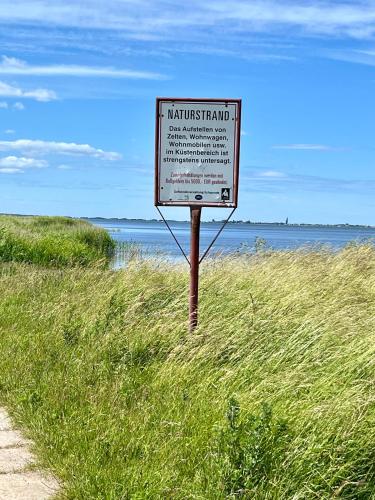 a sign in the grass next to a beach at Ferienhaus Rügen-Relax in Trent