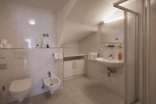 a white bathroom with a toilet and a sink at Residence Chiavi D'Oro - Goldener Schl&uuml;ssel in Bressanone