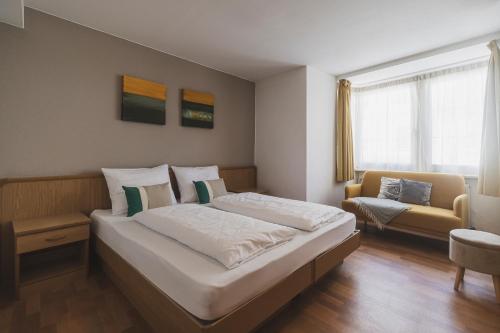 a bedroom with a large bed and a couch at Residence Chiavi D'Oro - Goldener Schl&uuml;ssel in Bressanone