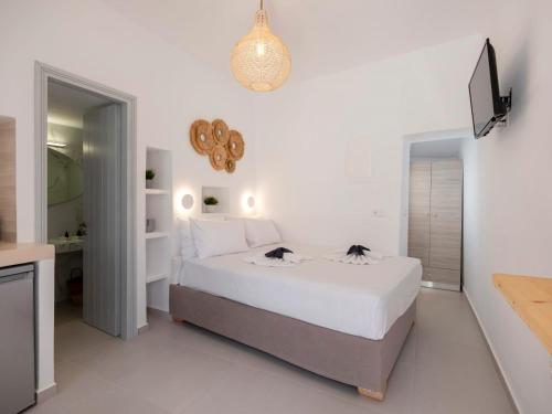 a white bedroom with a bed and a mirror at M&M Parikia's Old Town Studio in Parikia