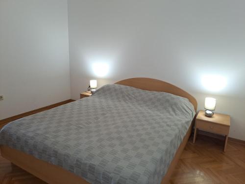 una camera da letto con un letto con due luci su due tavoli di Apartment Zarok 2 a Baška