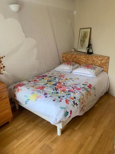 - un lit avec une couette à fleurs dans une chambre dans l'établissement maison en bois au bord de l'Hérault, à Saint-Bauzille-de-Putois