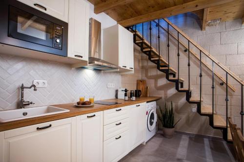 a kitchen with white cabinets and a staircase at Alexandras Stone House in Rhodes Town