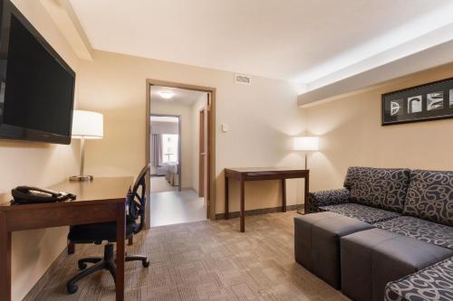a hotel room with a desk and a couch and a table at Days Inn by Wyndham Medicine Hat in Medicine Hat