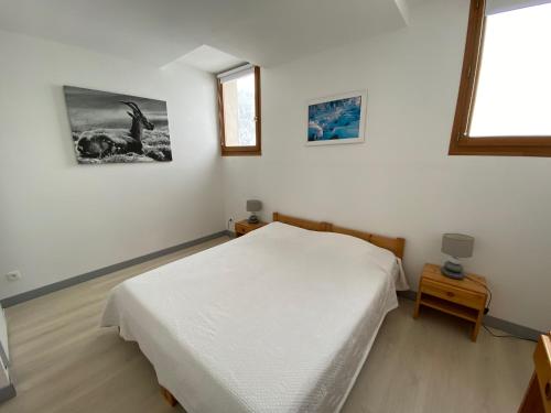 - une chambre avec un lit blanc, une table et une fenêtre dans l'établissement Résidence La Prairie, à Villard-de-Lans