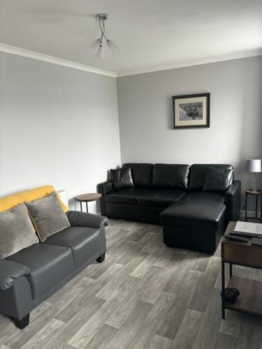 a living room with a black couch and a table at Sea Breeze Apartment Wick in Wick