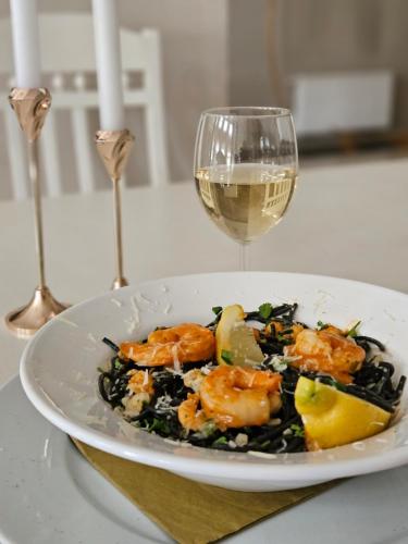a plate of food with shrimp and a glass of wine at Hotel Adler in Byczyna
