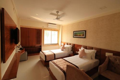 a hotel room with two beds and a window at The Hotel SAAJ-Premium in Bhubaneshwar