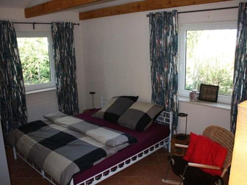 a bedroom with a bed and two windows at Morning sun Comfortable holiday residence in Westerstede