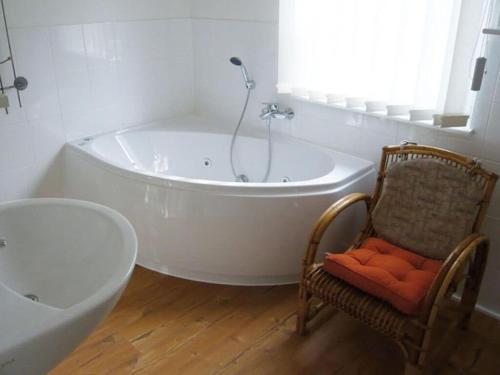 een witte badkamer met een bad en een stoel bij House Thor - Huus Asgard in Nieby