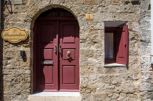 a red door on the side of a stone building at Alexandras Stone House in Rhodes Town