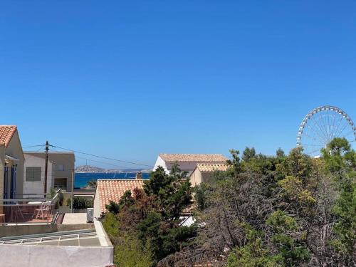 une grande roue au loin avec des maisons et des arbres dans l'établissement Maison bord de mer - 200m de la plage, à Marseille