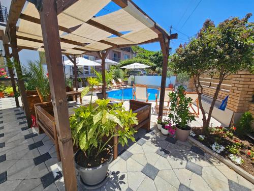 a wooden pergola with plants and a swimming pool at Villa Pegasus Pestani in Ohrid