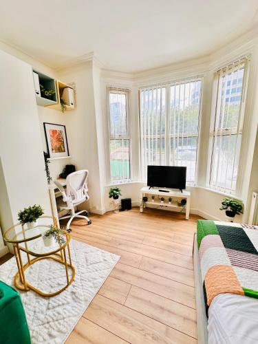 a living room with a bed and a flat screen tv at Stylish Private Room opposite Queen Elizabeth Hospital - Harborne Birmingham RA in Birmingham