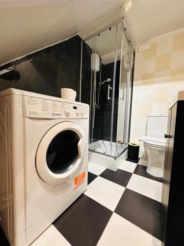 a washing machine in a bathroom with a checkered floor at Stylish Private Room opposite Queen Elizabeth Hospital - Harborne Birmingham RA in Birmingham