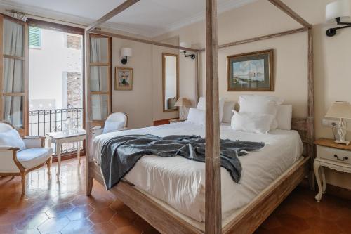 a bedroom with a four poster bed and a balcony at Hotel Can Abril in Sóller