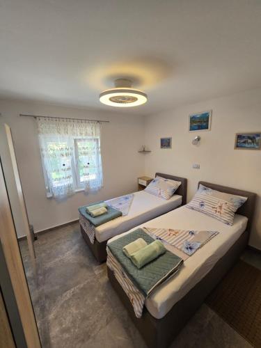 Un dormitorio con dos camas y una ventana. en Apartmani Plavšić, en Novi Vinodolski