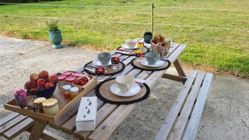 a picnic table with cups and plates of food on it at Relais équestre du Miloir - chambres d'hôtes in Saint-Désir
